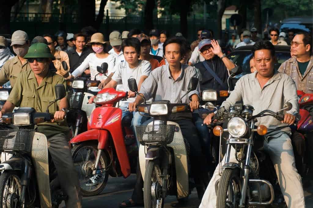 Vietnamese locals in Hanoi on motorbikes at a junction ready to start their engines