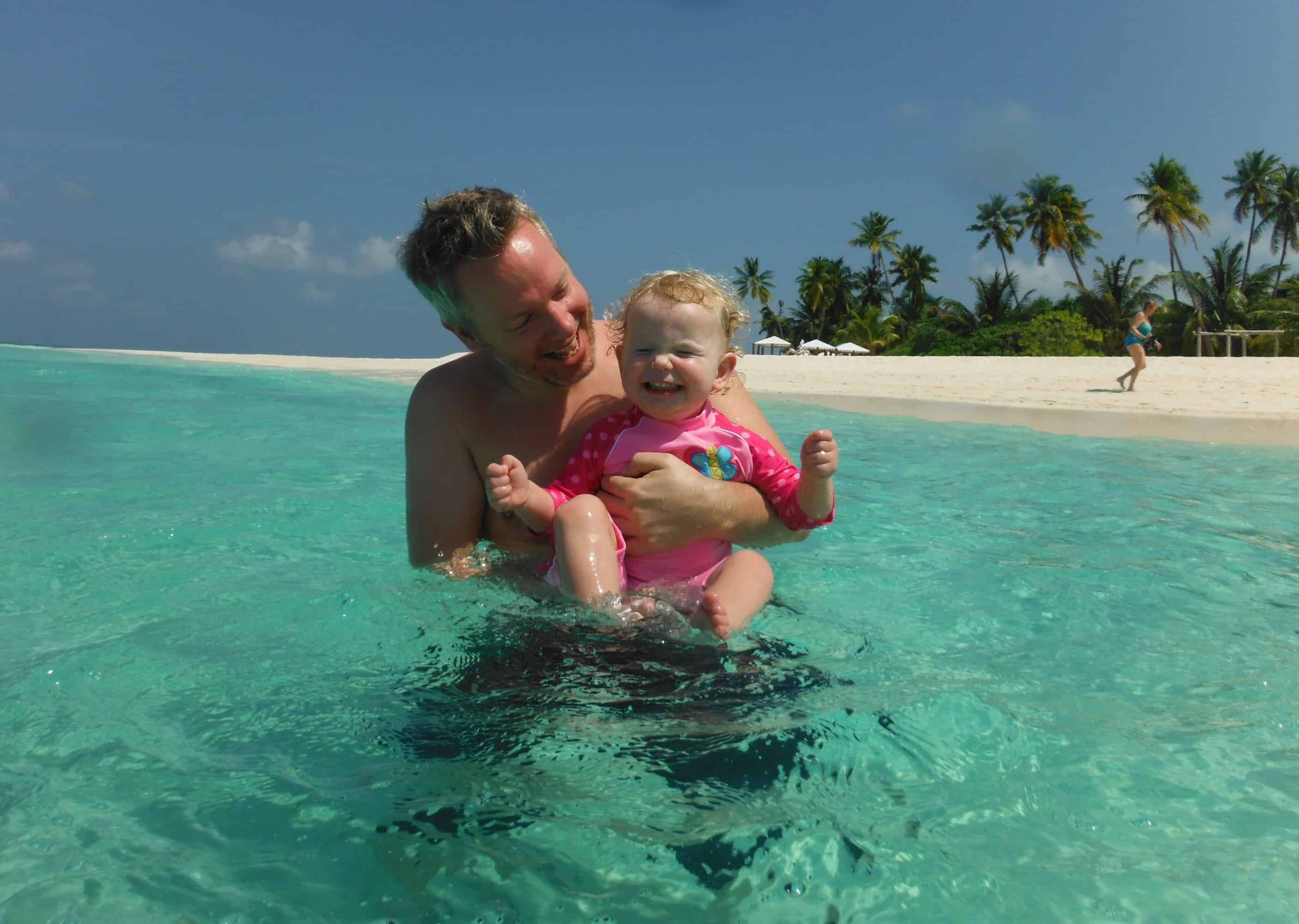 Young child and father in the turquoise sea on a family holiday to the Maldives