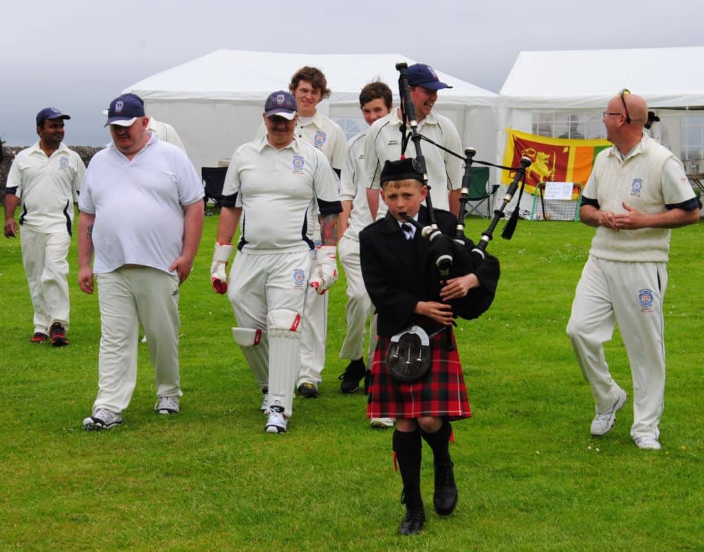 Dr. Lilantha Wedisinghe from the Sri Lanka Association and his team are lead on to the field by a Scottish piper. 