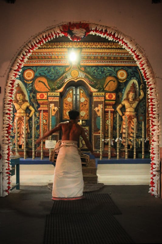 A Kandyan dancer in front of a shrine at the devale (temple)