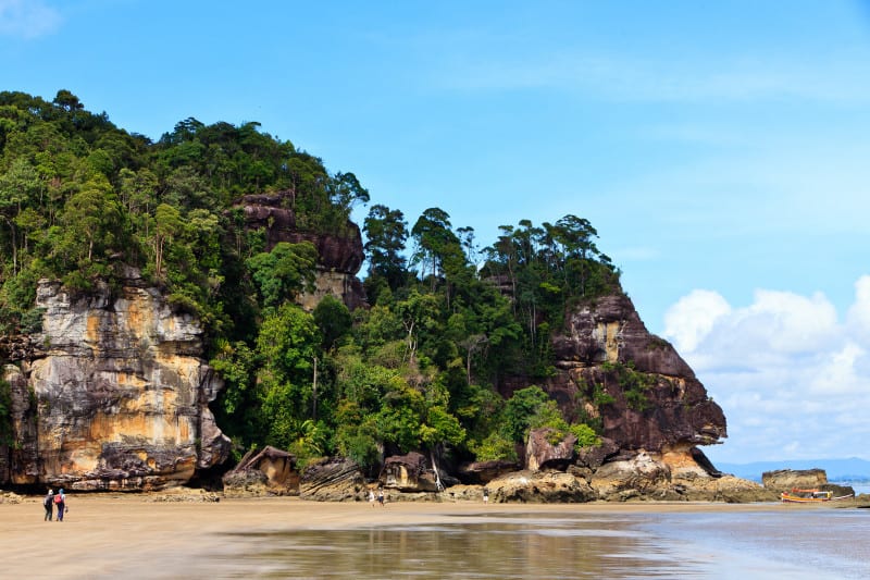 Coastal landscape of Bako National Park with beach in the foreground and forests, rocks and hills in the background