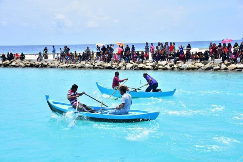 Two boats with two rowers in during a bohkuraa race in the sea with crowds watching
