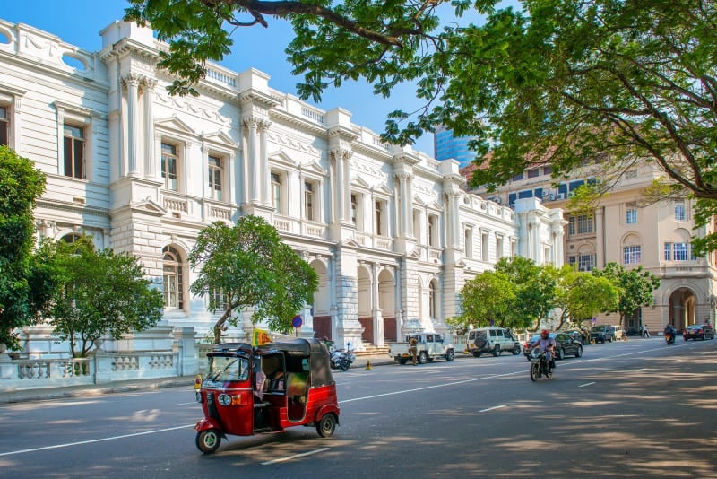 White exterior of Foreign Affairs Ministry Building in Colombo with tuk tuk driving past