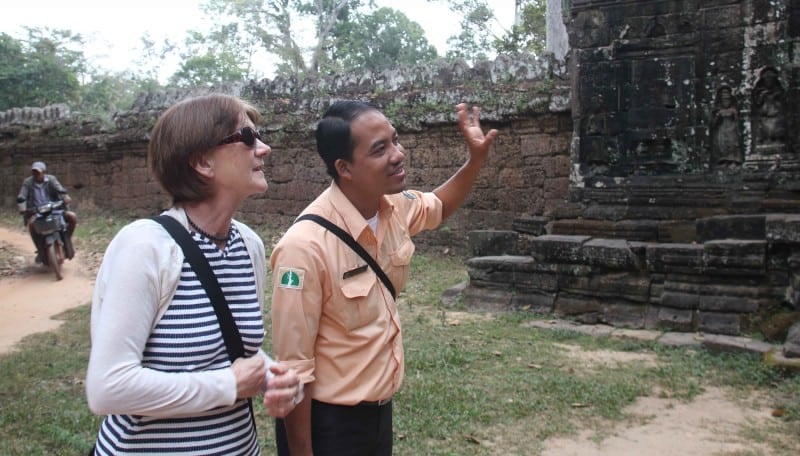 A guide talking to a traveller in cambodia whilst pointing at a monument