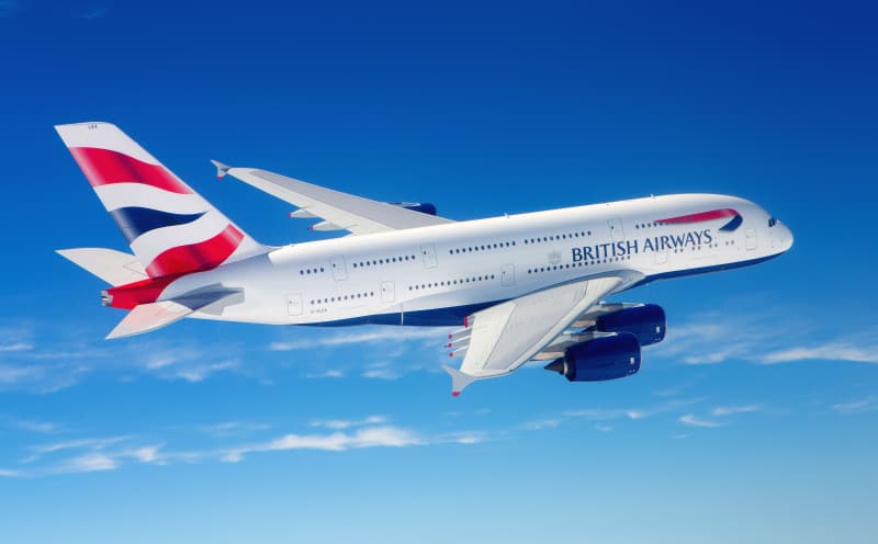 british airways plane in the blue sky with a few thin clouds below the plane