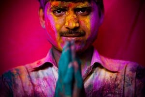 man with his palms together covered in colour after celebrating holi festival