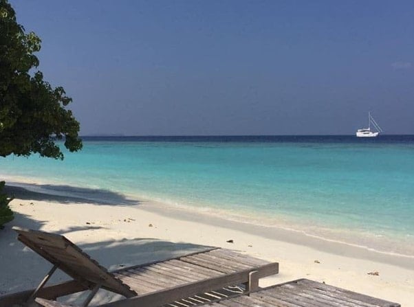 lounge chairs on the beach in the Maldives overlooking the turquoise blue waters