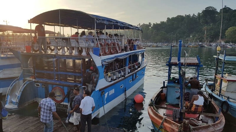 a view from the dock of a boat with two tiers with tourists on the top tier
