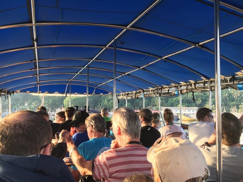 tourists on a crowded boat with a canopy covering them from the sun