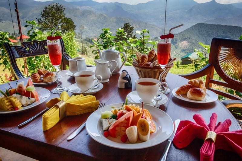 A typical breakfast at Madulkelle Tea and Eco Lodge with a beautiful view of hills in the background