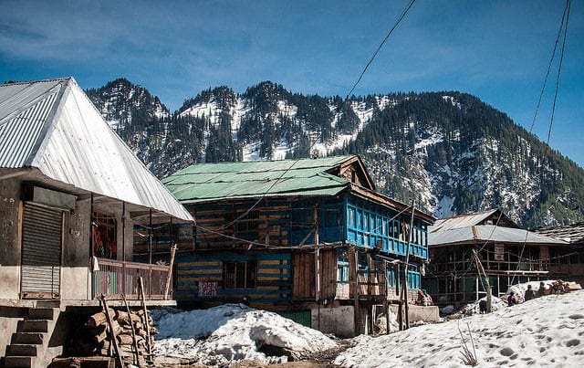 Malana Village in Himachal pradesh with forests, snow clad hills in the background