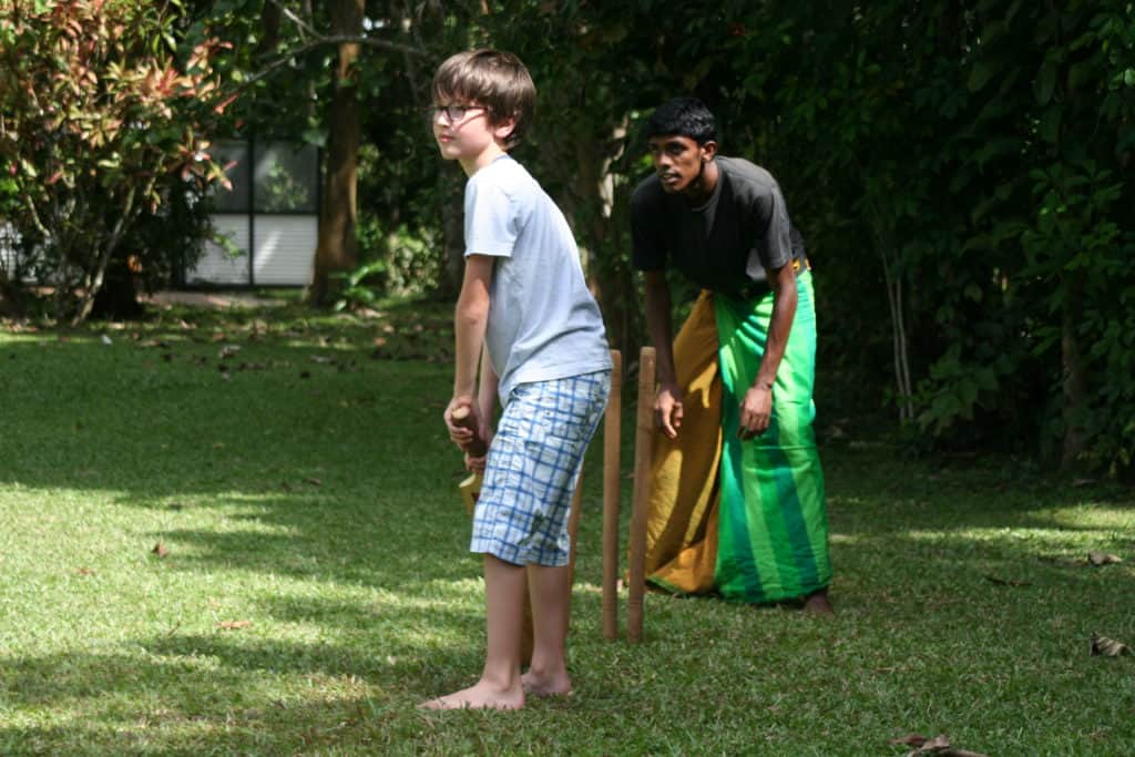 Child playing cricket with locals in Sri Lanka