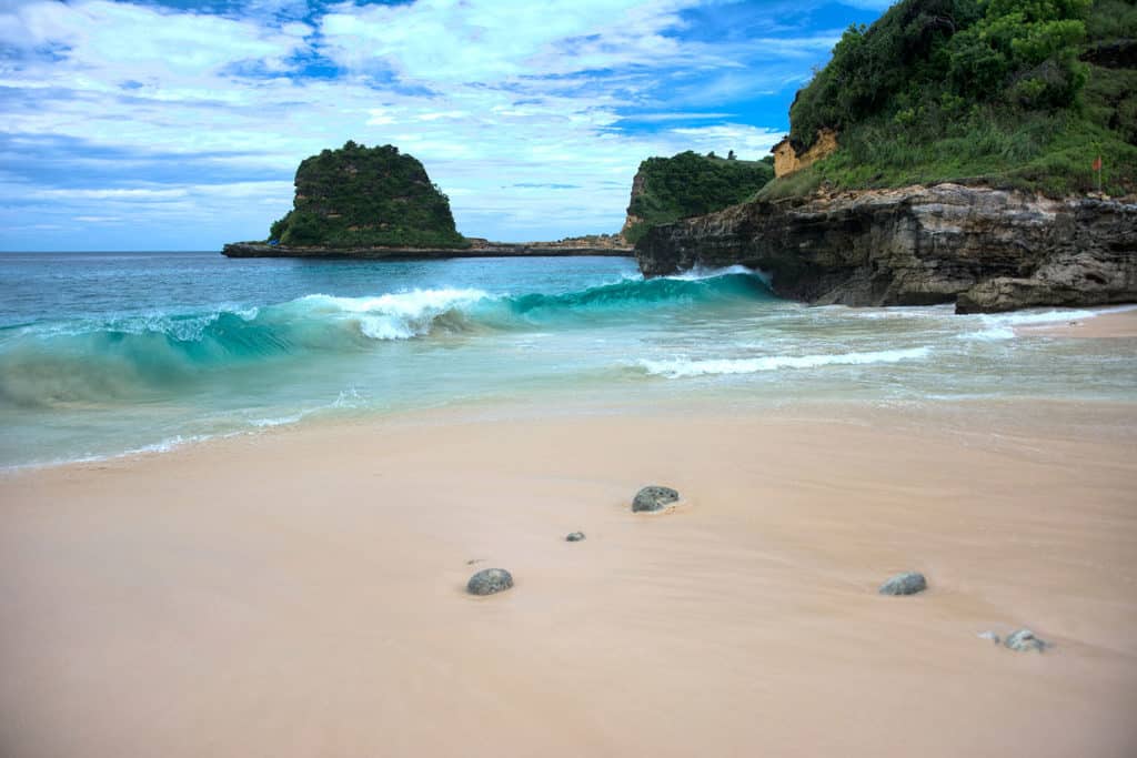 Remote beach on Lombok with rocky outcrops heading into the ocean