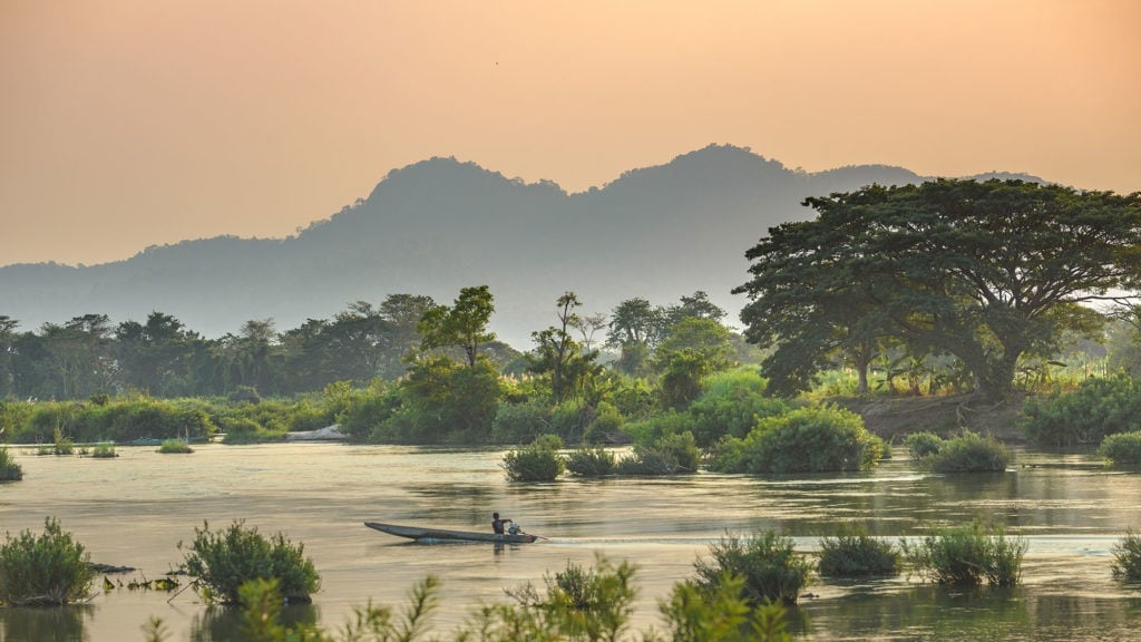 A fisherman floats along the mekong river around 4000 islands in Laos at dusk