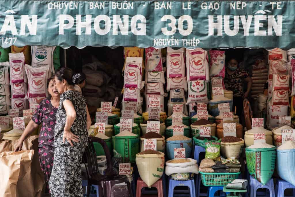 Shop front scene with awning hanging over spice being sold with two Vietnamese women talking in front