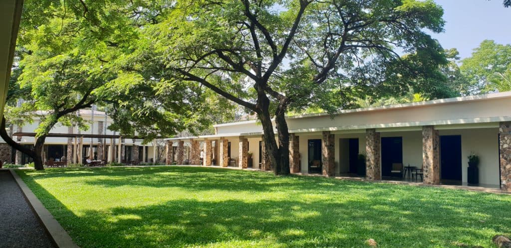 The grass courtyard of Amansara in Siem Reap with trees creating shade