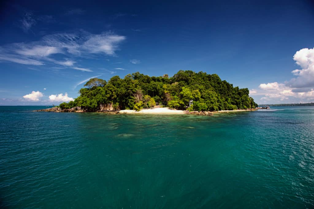 a tropical island opposite koh krabey covered in forest with a small white sand beach
