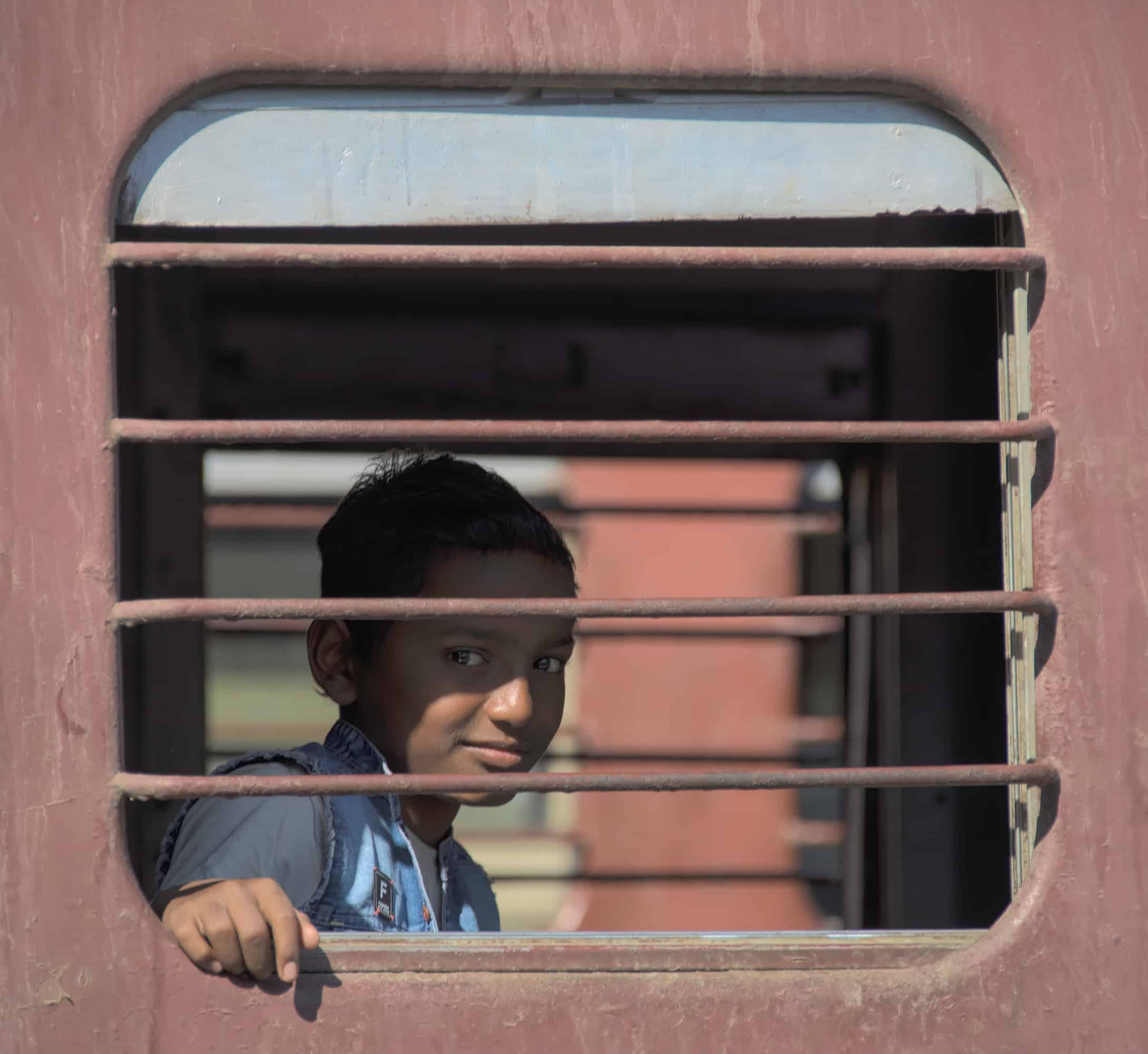 Boy on a train in India looking out of window