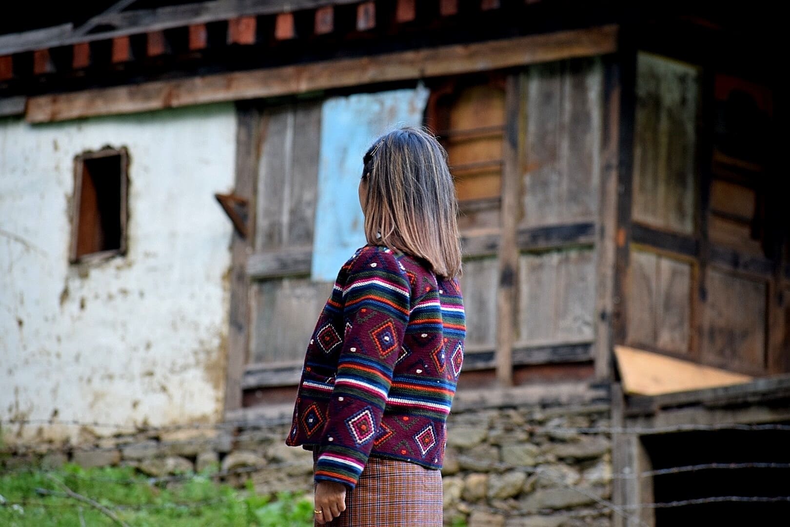 Woman turned away from the camera wearing a traditional Bhutanese weaving jacket