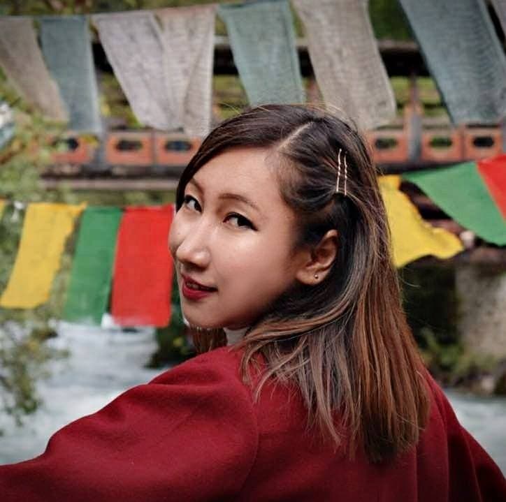 Founder of Bhutanese fashion label Geymit Lepcha in front of prayer flags