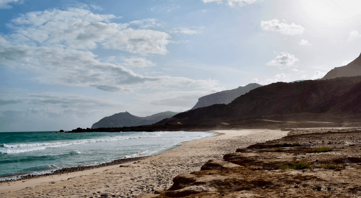 Beautiful beach in Oman with ocean and waves and mountains in the background