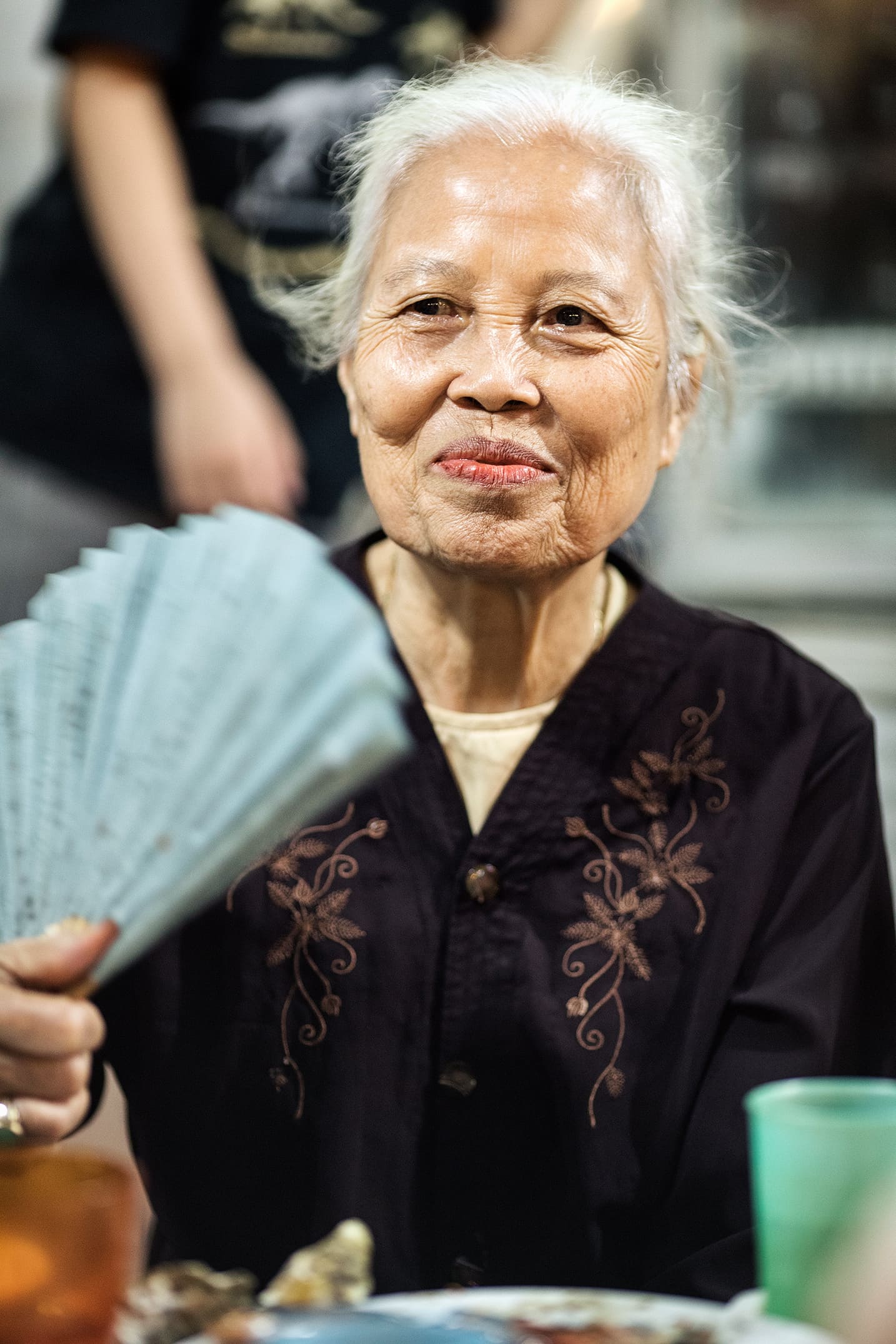 Old local woman eating Street food in Hanoi in the evening