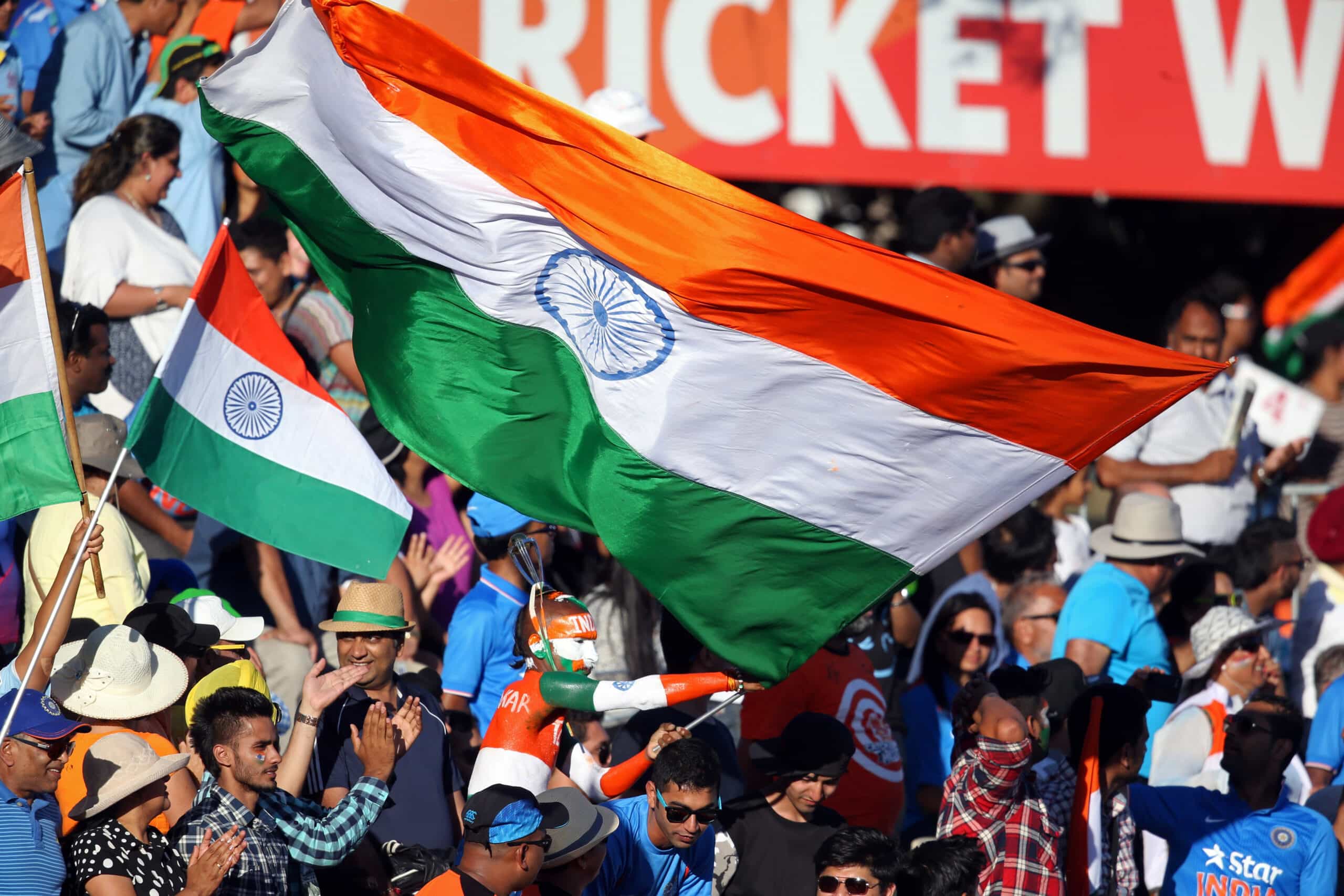 Indian cricket fans celebrating and flying a huge flag of India