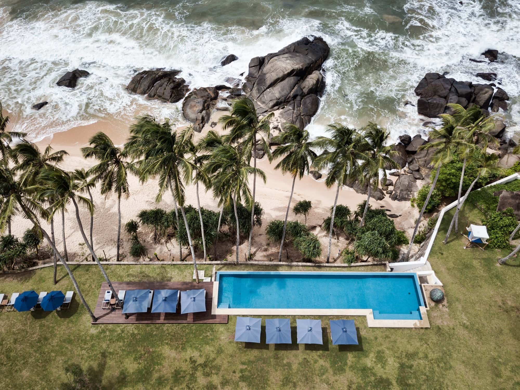 Aerial shot of Kumu Beach swimming pool with palm trees and rocky beach