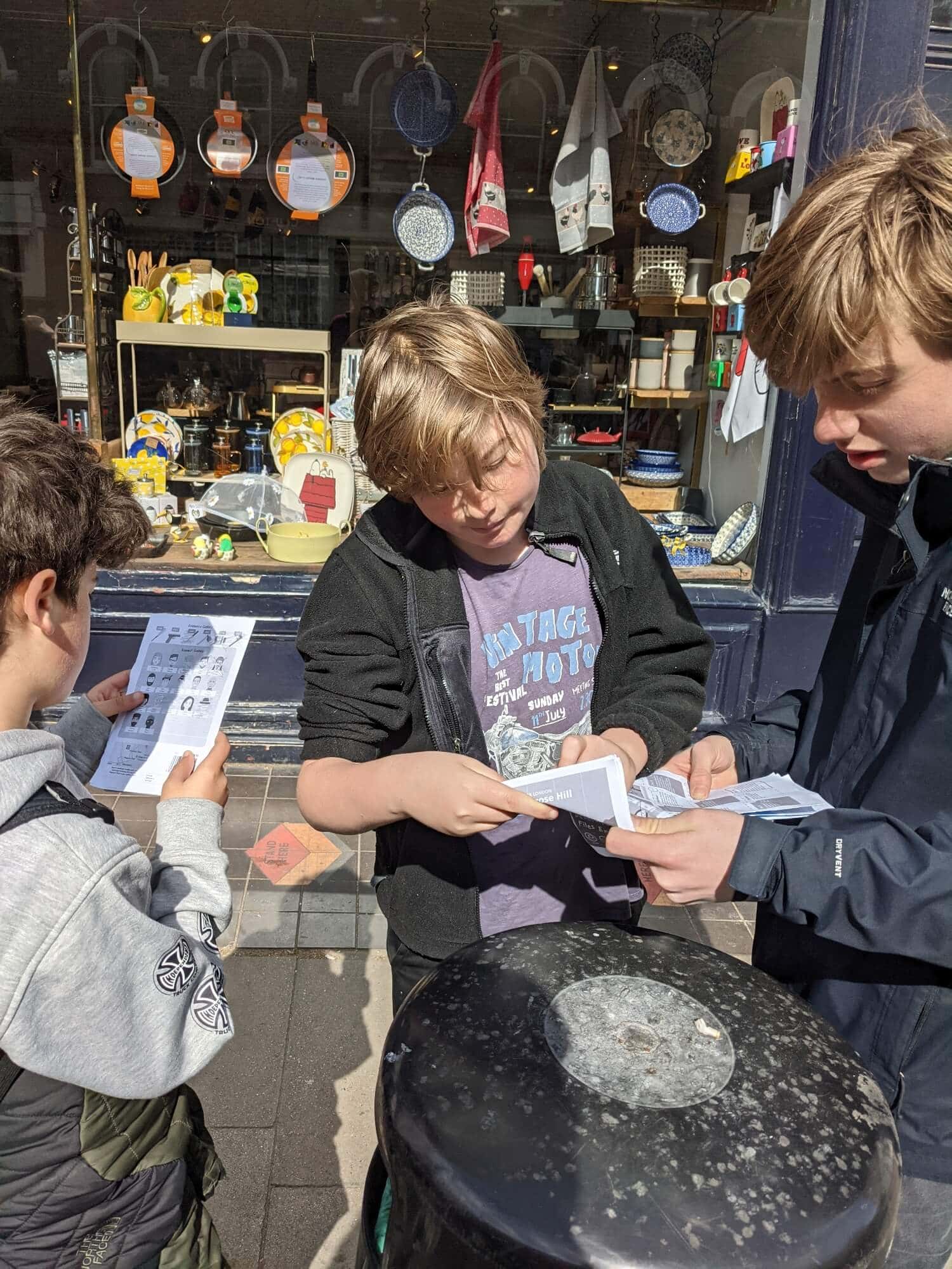Three teenage boys reading maps on a London street