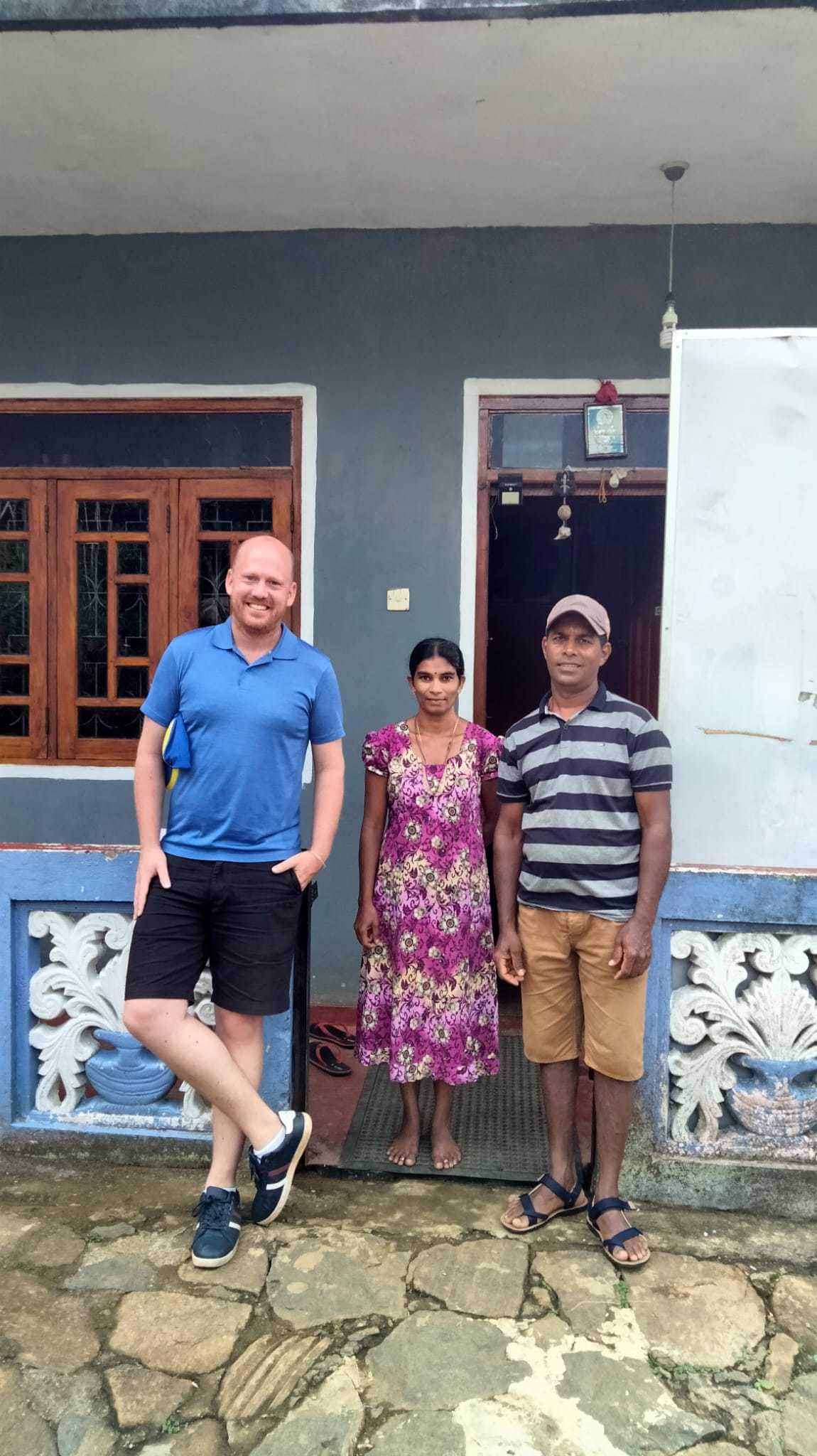 Tamil Husband and Wife with tourist outside their simple house in the tea plantations of Haputale