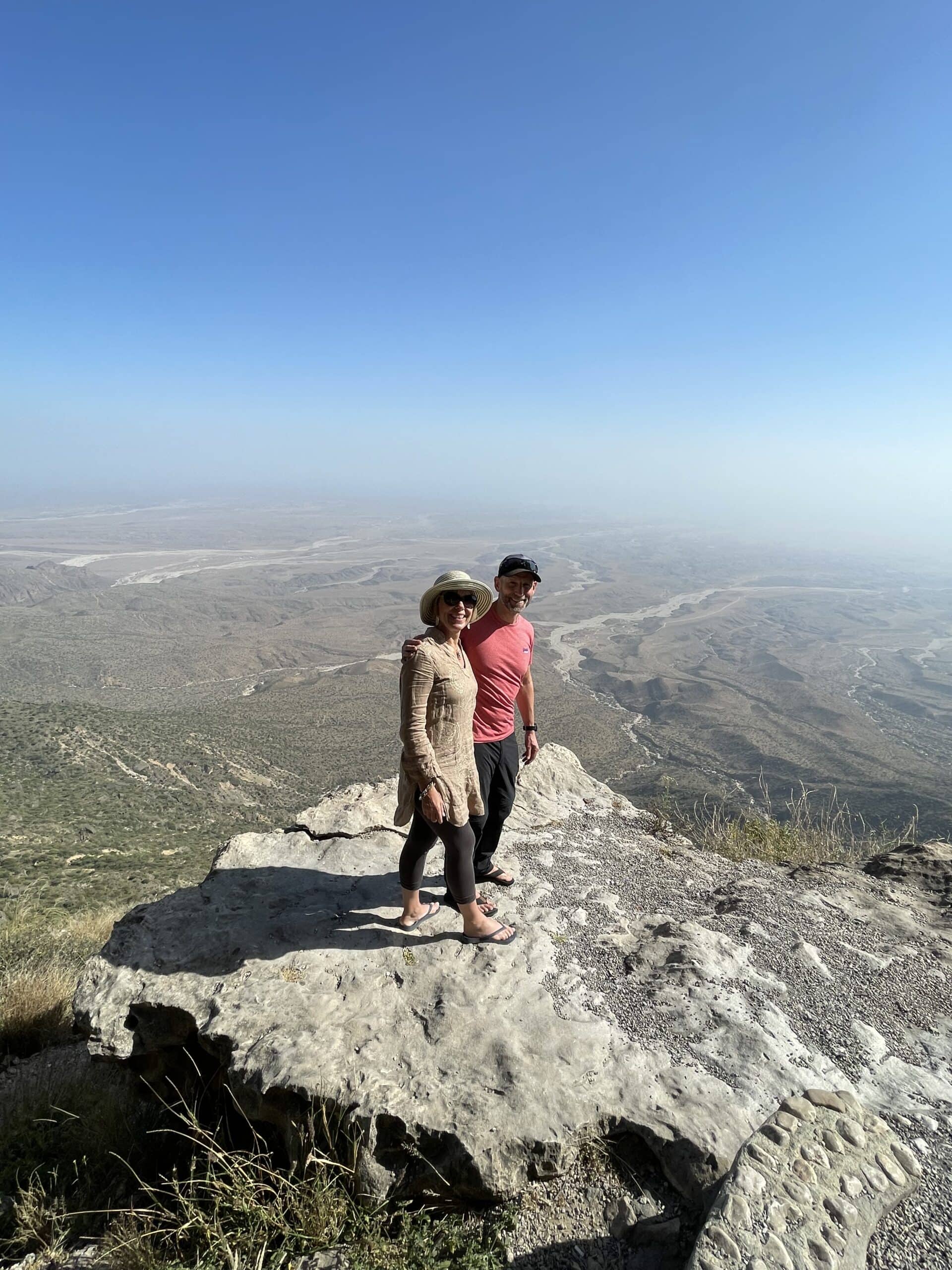 Travellers on a rock at 1700m above sea level in Oman with blue sky in the background