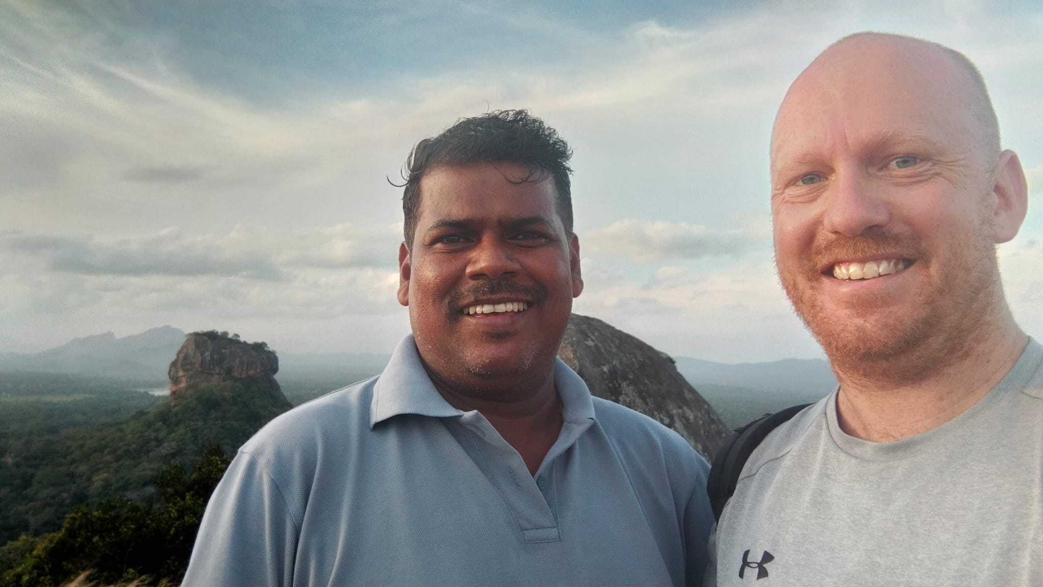 A selfie of a traveller and guide on top of Pidurangala with Sigiriya in the background