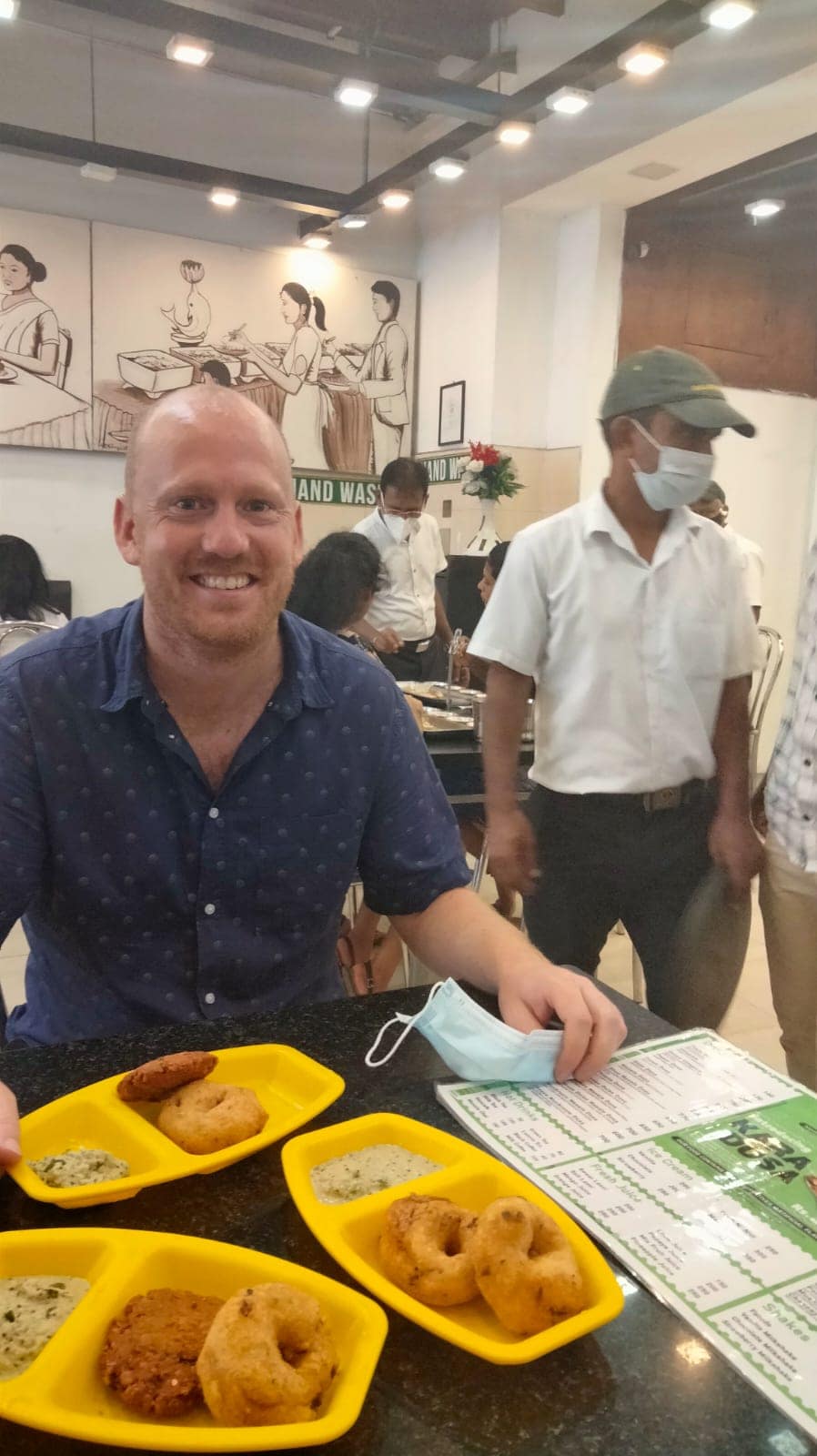 A traveller eating in a restaurant in Kandy with staff wearing masks in the background