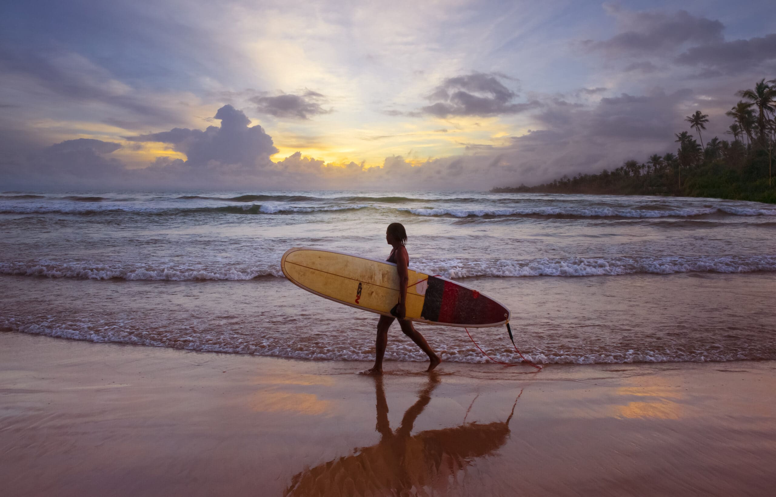 Unawatuna, Sri Lanka, Girl on the beach holding her surfboard