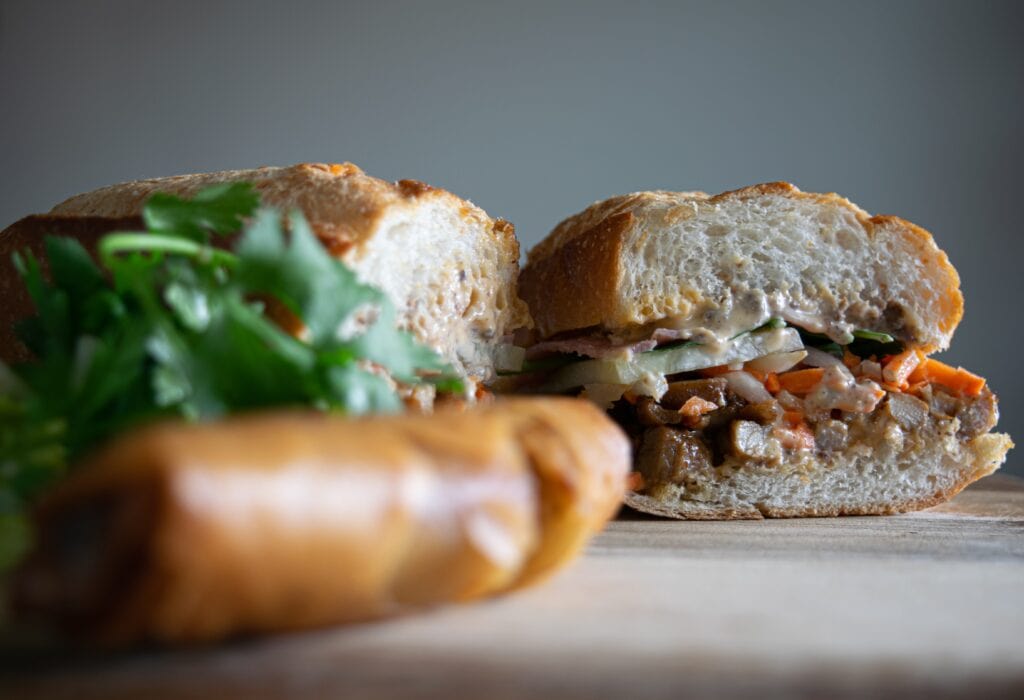 A Banh Mi lying on a wooden chopping board.