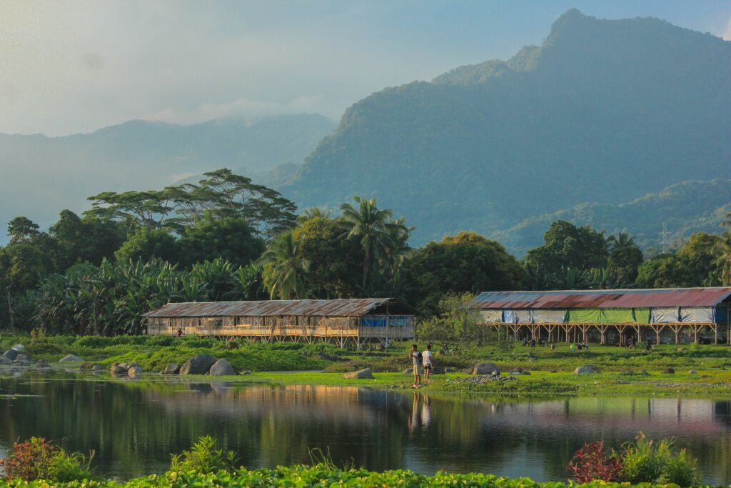Wooden buildings surrounded by greenery near a lake in Ende, Indonesia