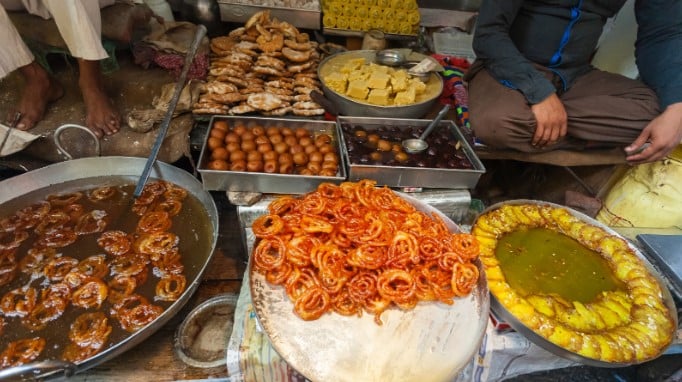 Street food stall cooking and serving Indian sweet desserts