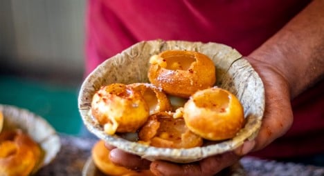 A person holding a bowl of Puchkas an Indian hollow snack