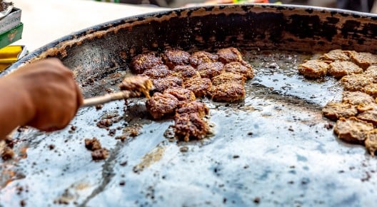 Circular kebabs being cooked on a hot plate