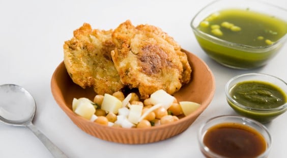 A bowl of Aloo Tikki an Indian potato patty served with a selection of chutneys