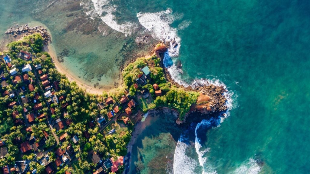 Aerial shot of a coastal Sri Lankan town with waves hitting the shore