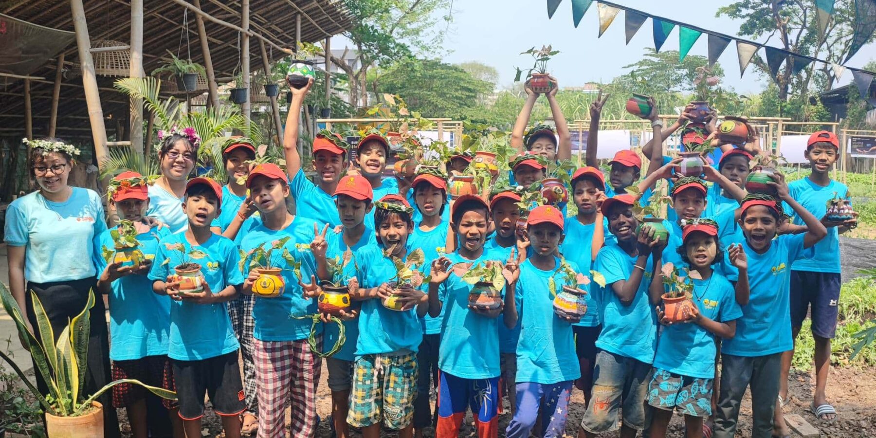 A beaming group of children holding their farming projects at Kokkoya Organics Urban Farm in Yangon, Myanmar