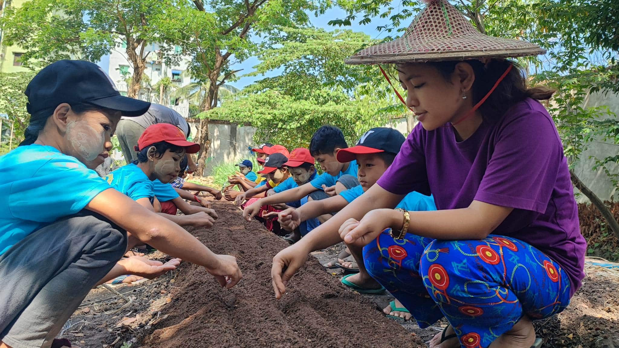 A row of happy children learn about organic farming at Kokkoya Organic Farm, Yangon, Myanmar
