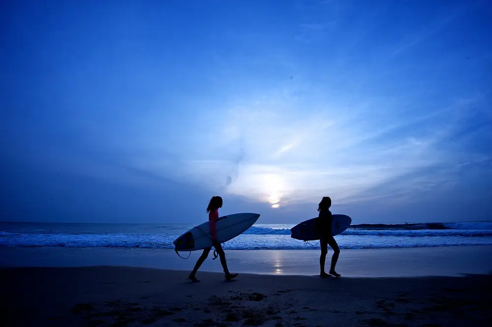 Surfers walking along Kottukal beach at sunset in Sri Lanka