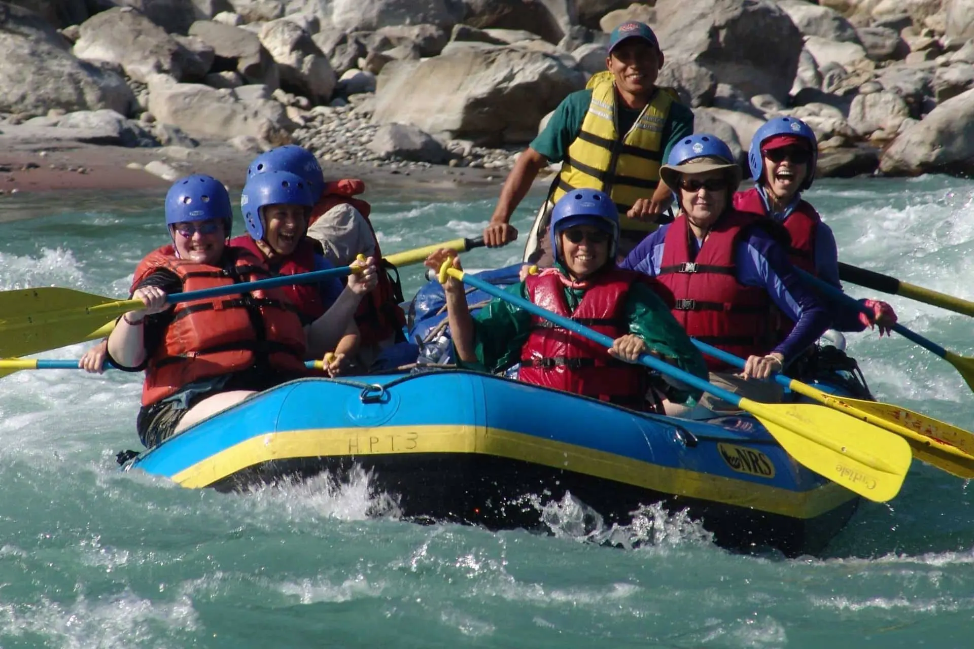 Family rafting on the Trishuli River in Nepal wearing helmets and life jackets during a white-water rafting adventure.