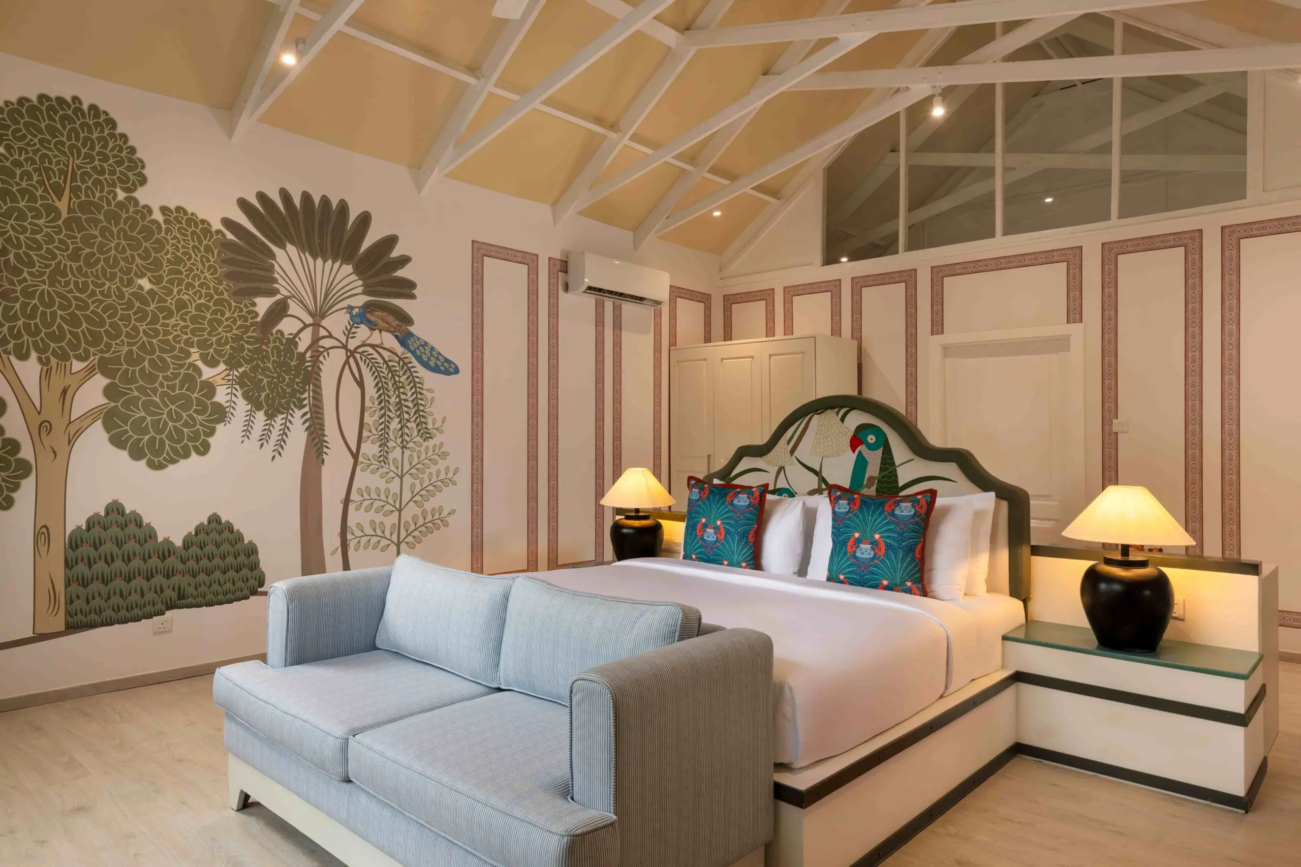 Stylish bedroom at Uga Jungle Beach with high ceilings and hand-painted wall art