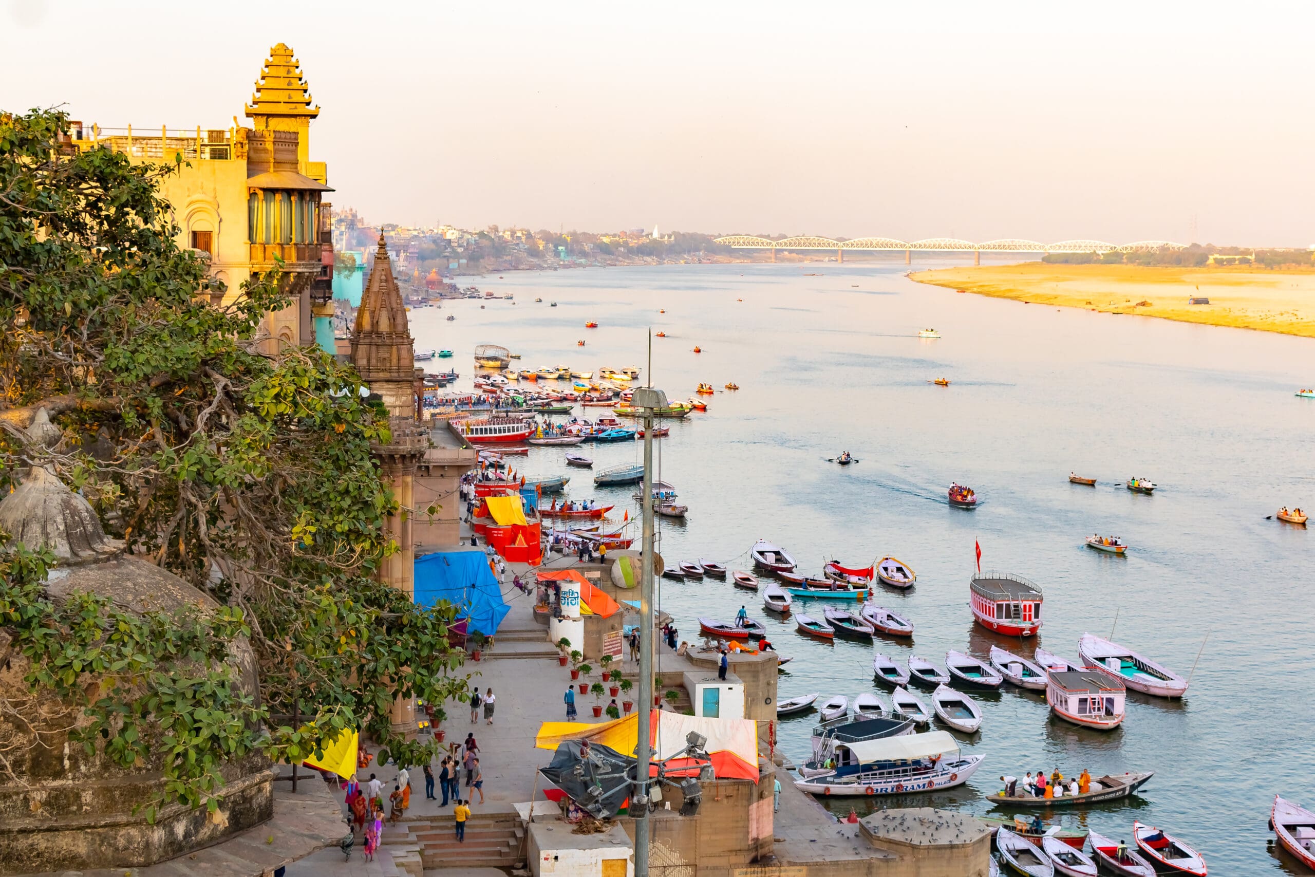Varanasi Ganges river ghat with ancient city architecture as viewed from a boat on the river at sunset.