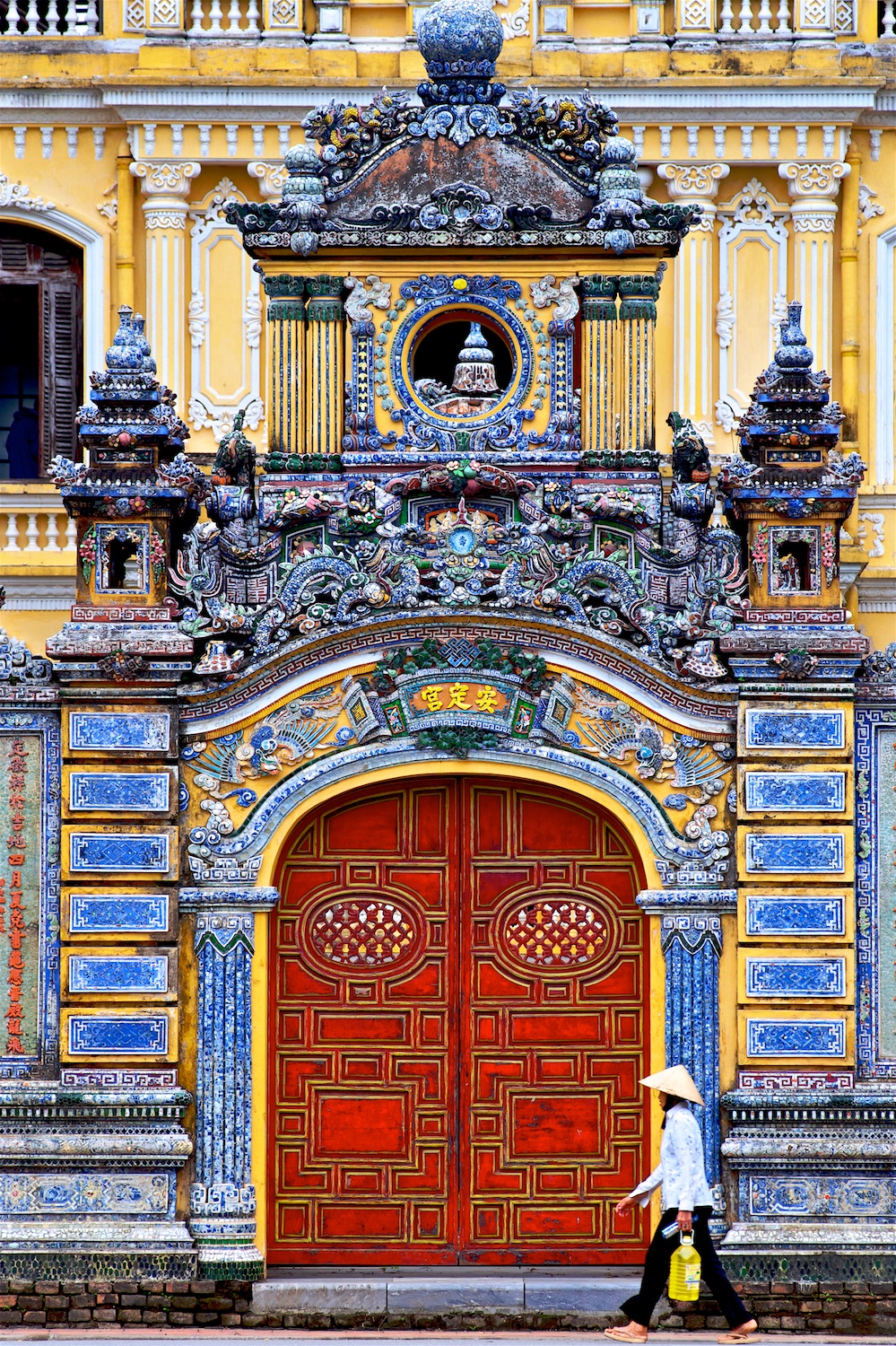 A local woman strolls past the recently restored An Dinh Palace in Hue, the former home to Emperor Bao Dai's mother