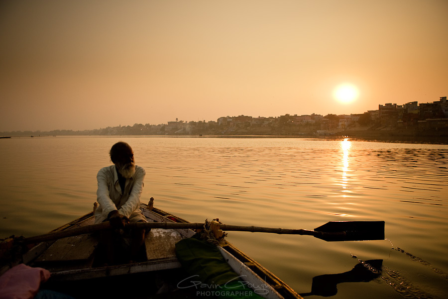 A ferryman rowing his ferry up the river Ganges in Varanasi at sunset