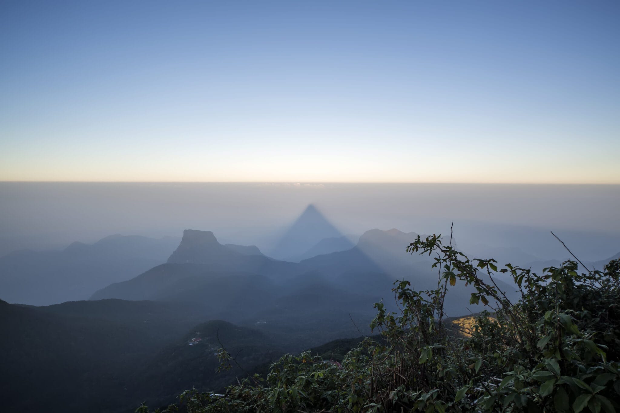 Adam's Peak at sunrise in the highlands of Sri Lanka, showing the perfect triangle shadow